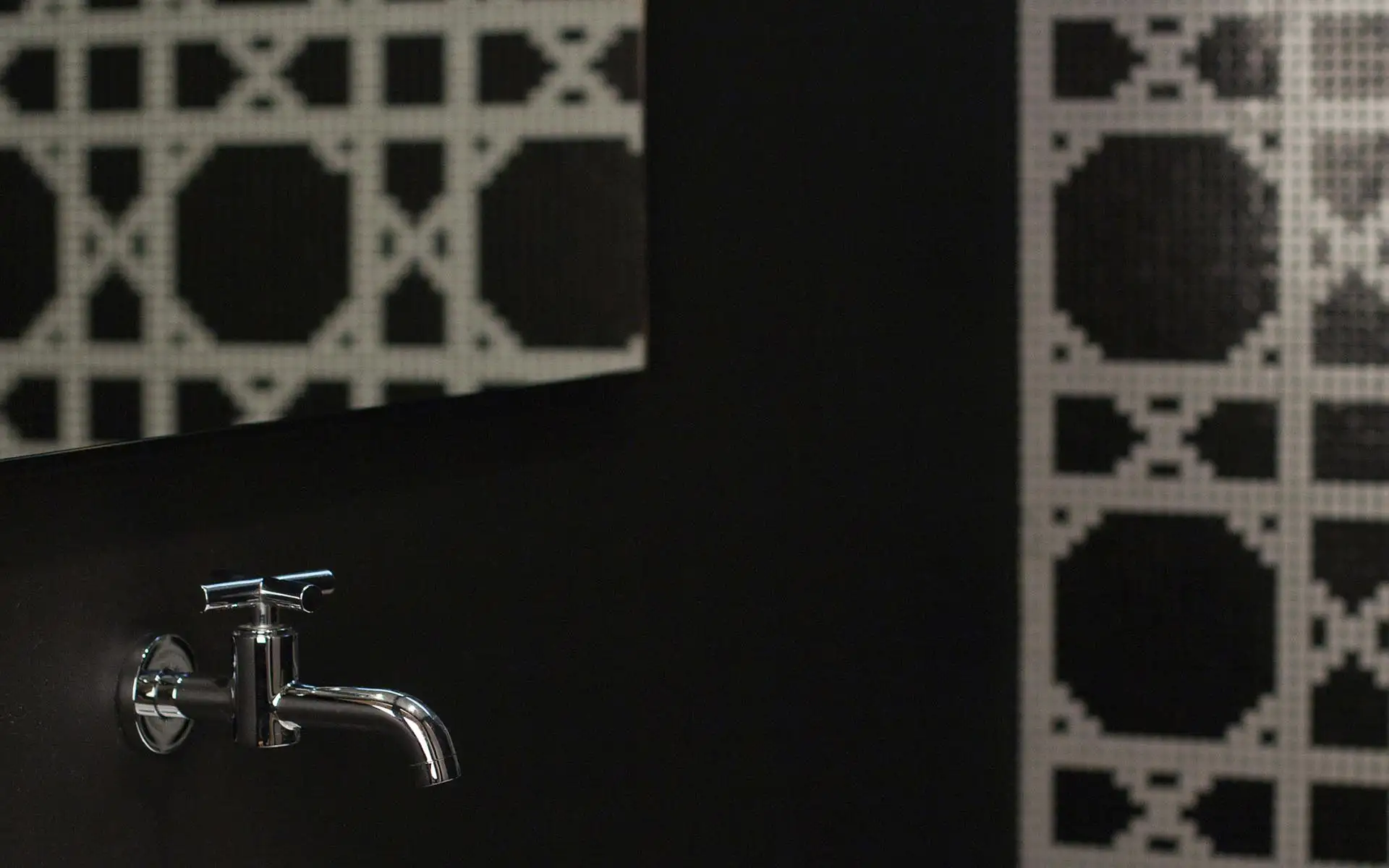 Wandfläche mit strukturiertem Muster und Armaturdetail in einem modern gestalteten Innenraum.