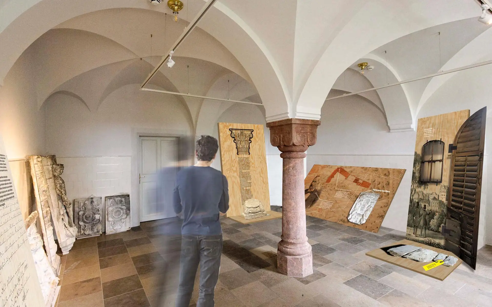 Ausstellungsraum mit Gewölbedecke, Mittelsäule und mehreren Informationstafeln