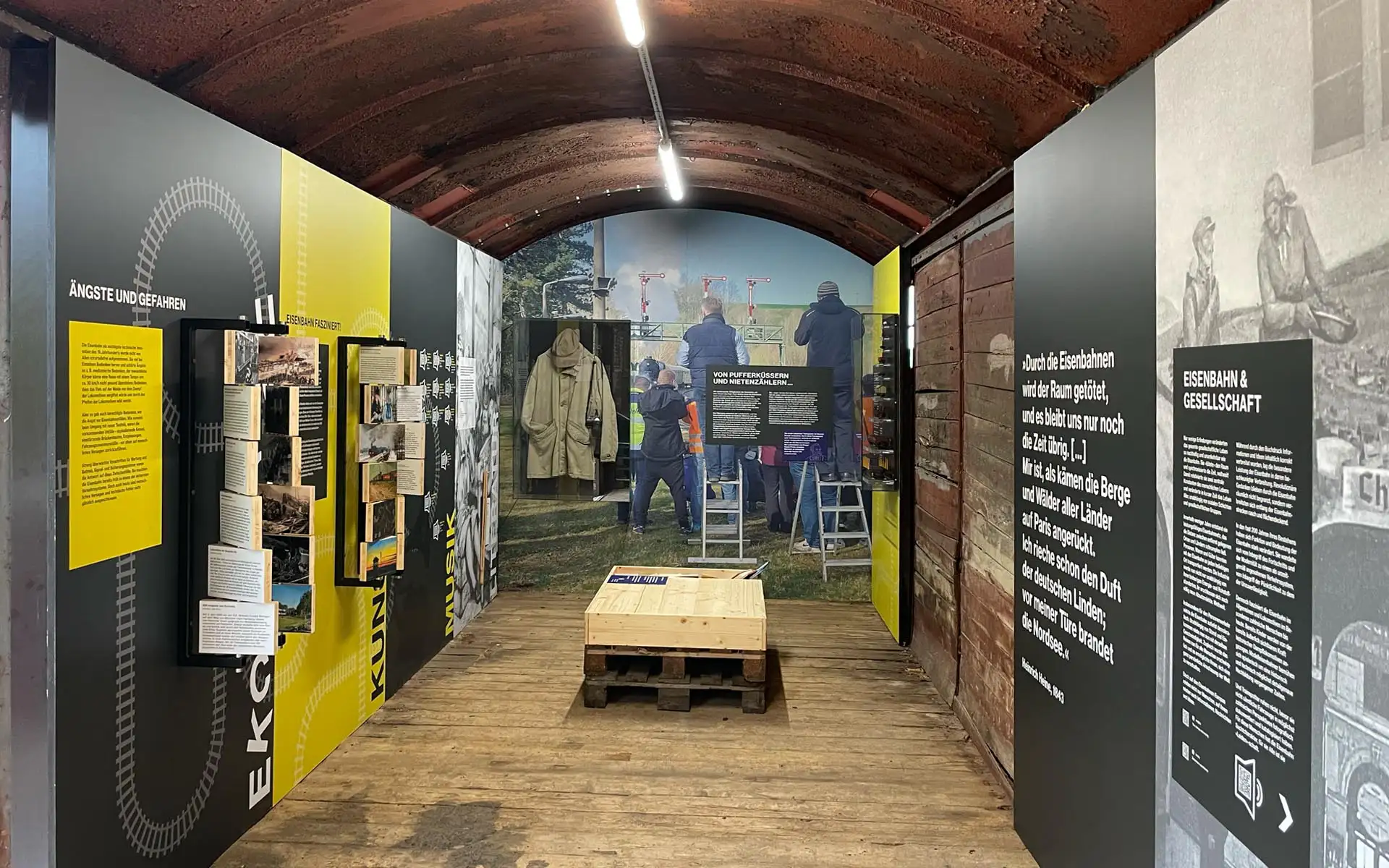 Ausstellung im Waggon mit Tafeln, Holzboden und Paletten