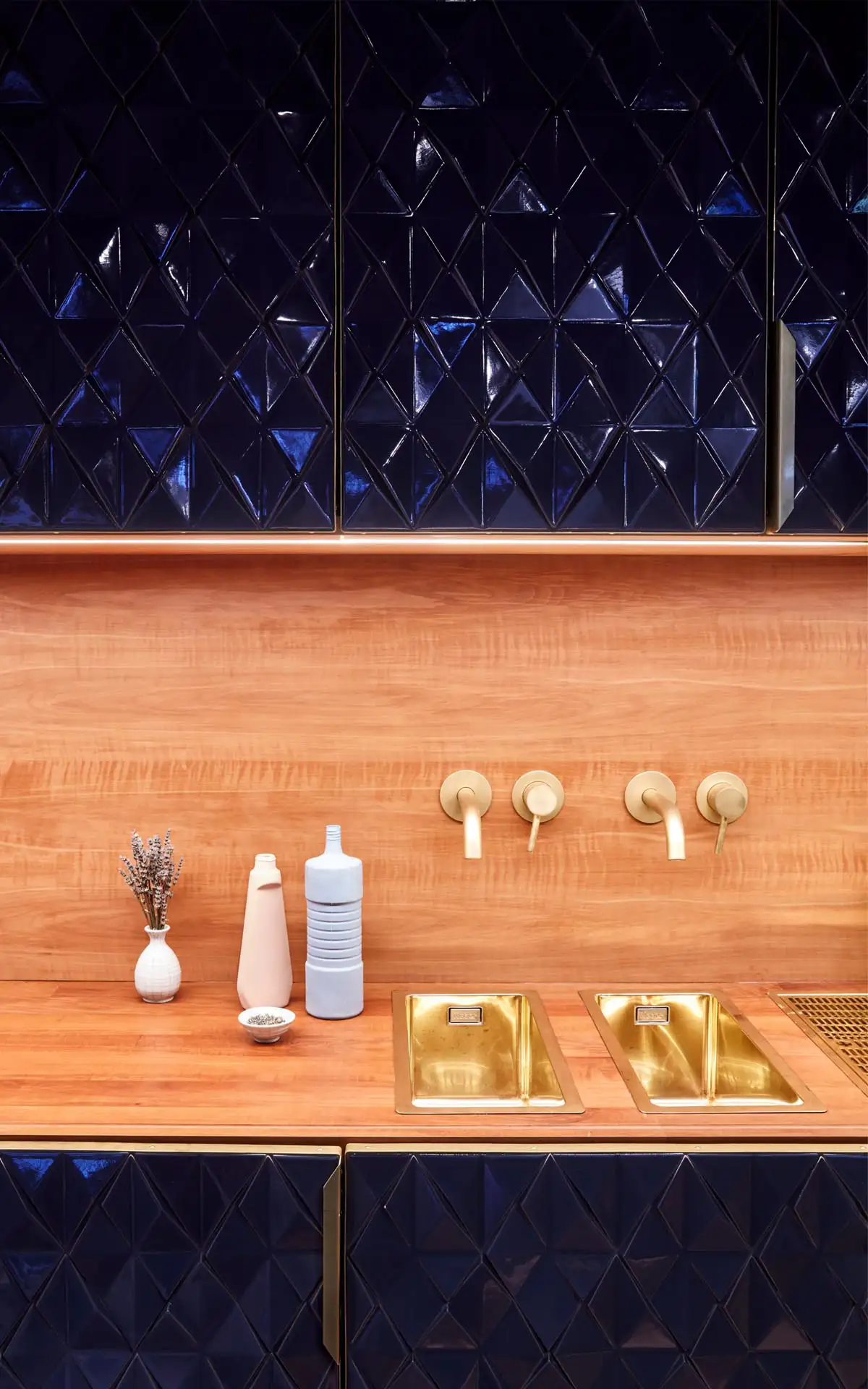 Barbereich mit Holznischen, goldenen Armaturen und glasierten dunkelblauen Fliesen.