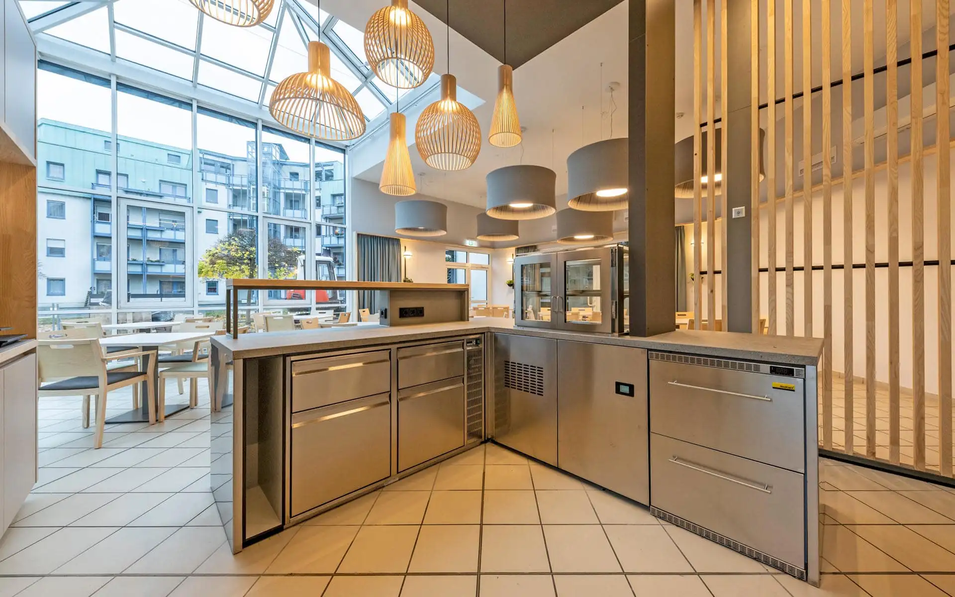 Heller Gastraum mit großen Fensterflächen, Sitzbereich und Blick auf die funktional gestaltete Theke.