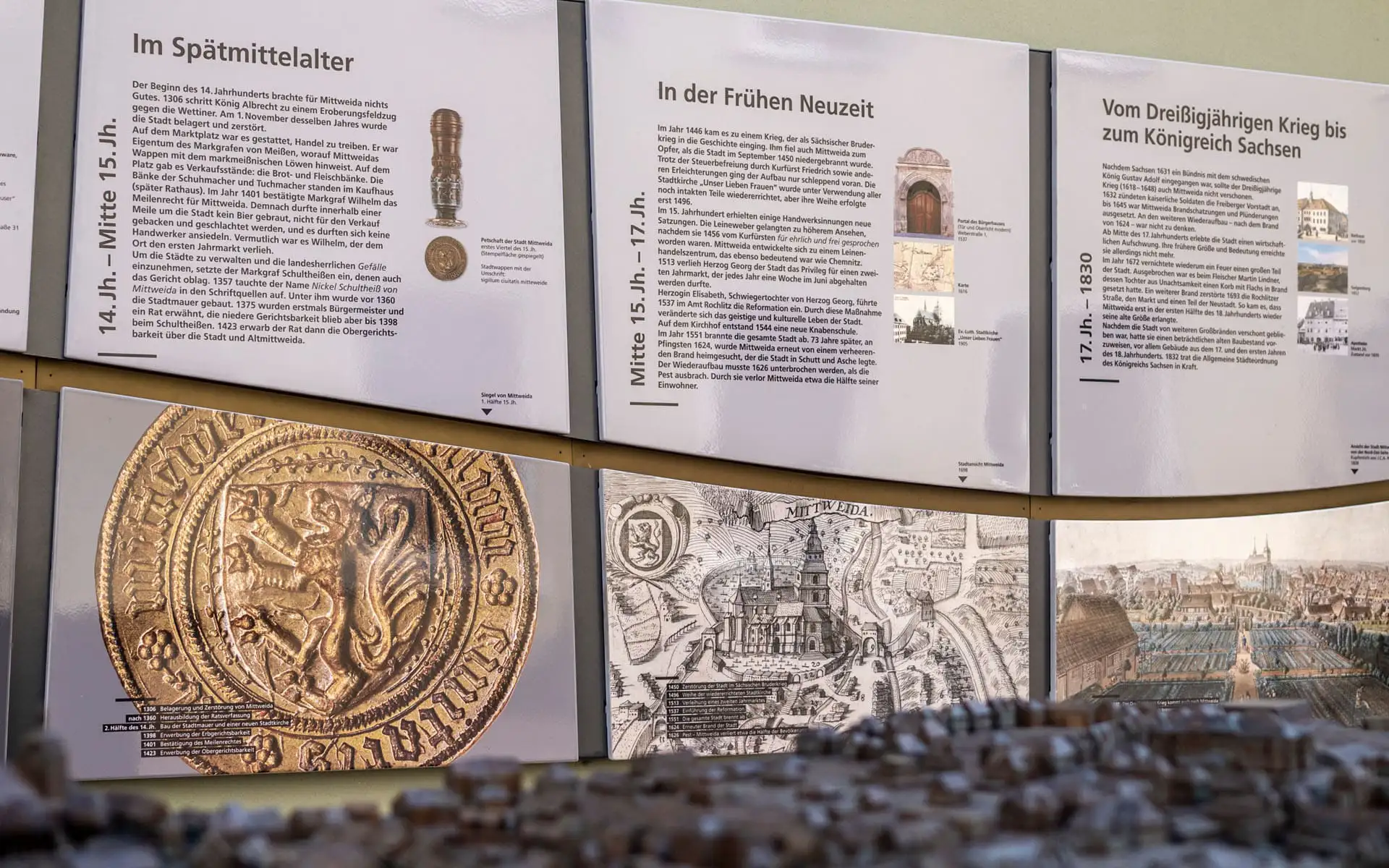 Wand mit historischen Tafeln und Stadtansichten.