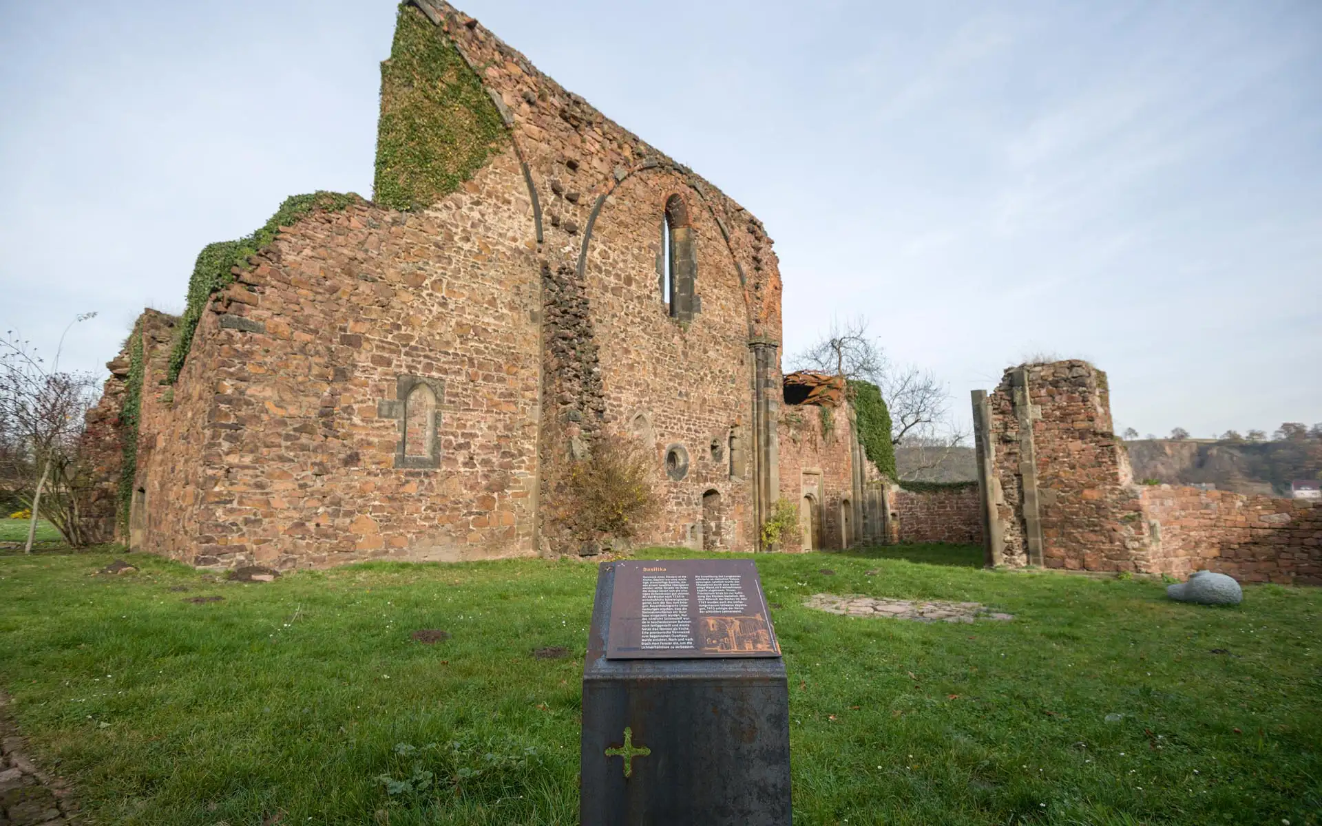 Ruine der Nonnenkirche mit Informationsstele im Vordergrund auf einer Wiese