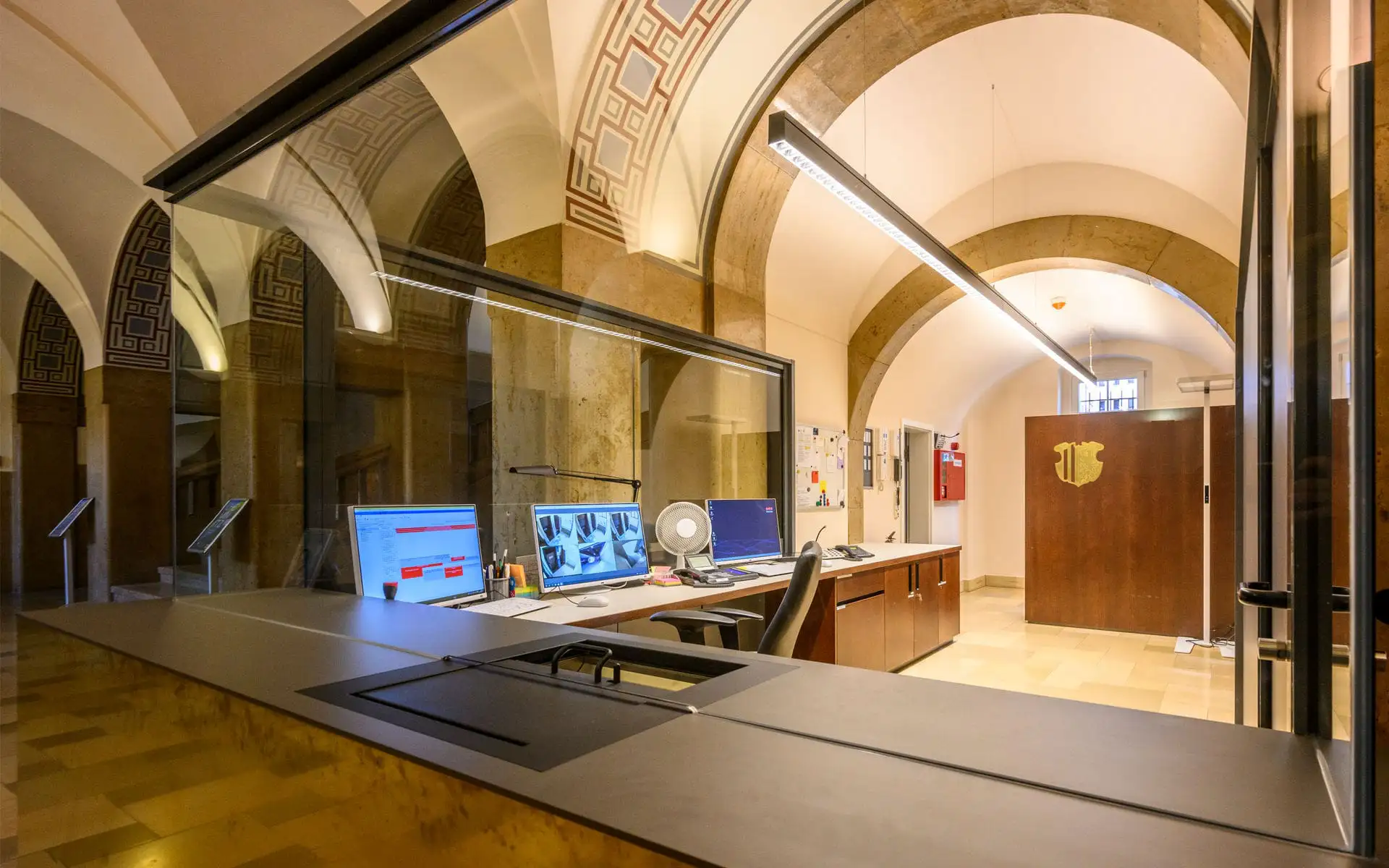 Empfangs- und Informationsbereich mit Messingverkleidung und Glasaufsatz