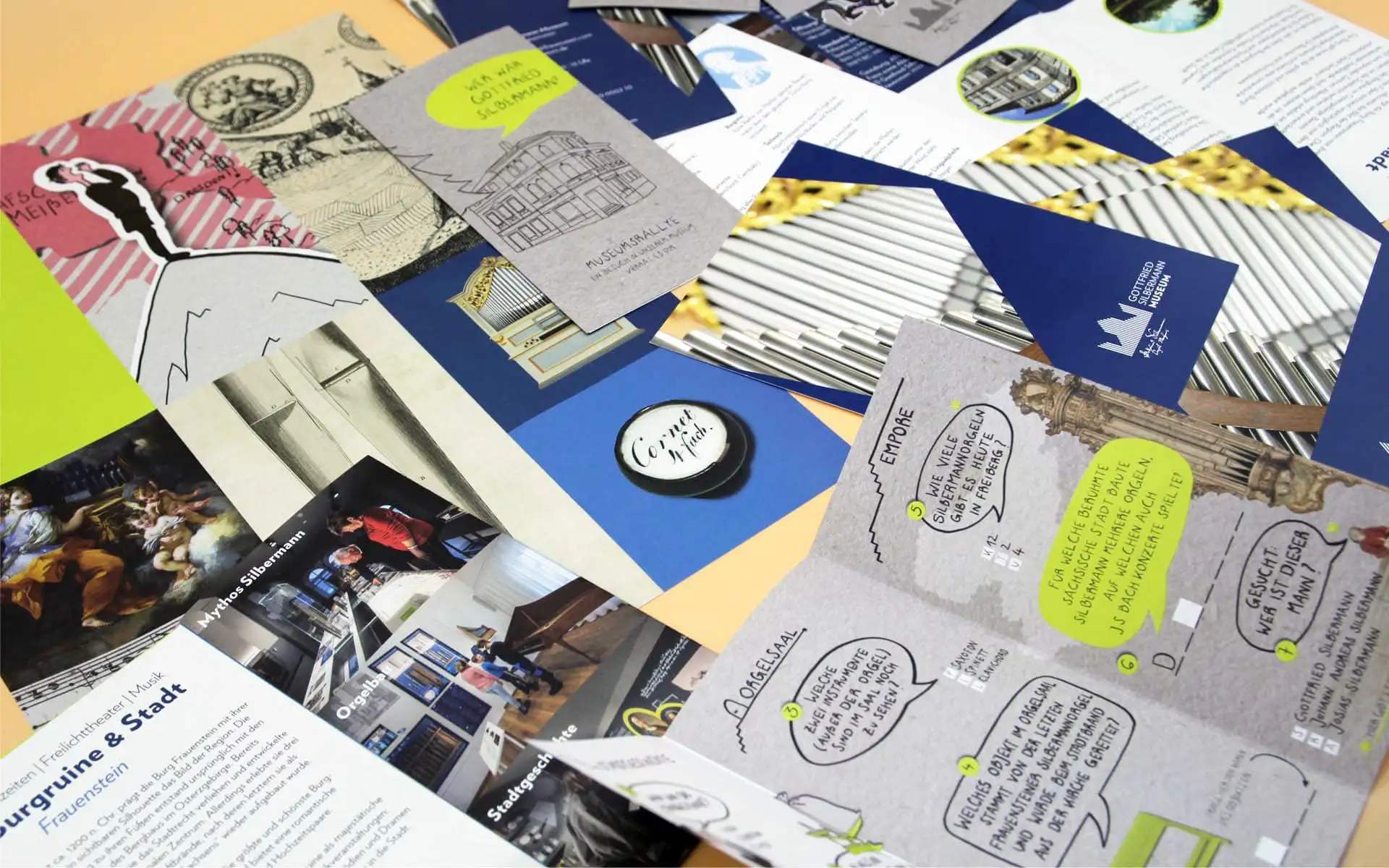 Verschiedene Printmaterialien des Museums Silbermann mit Illustrationen, Sprechblasen und historischen Motiven.