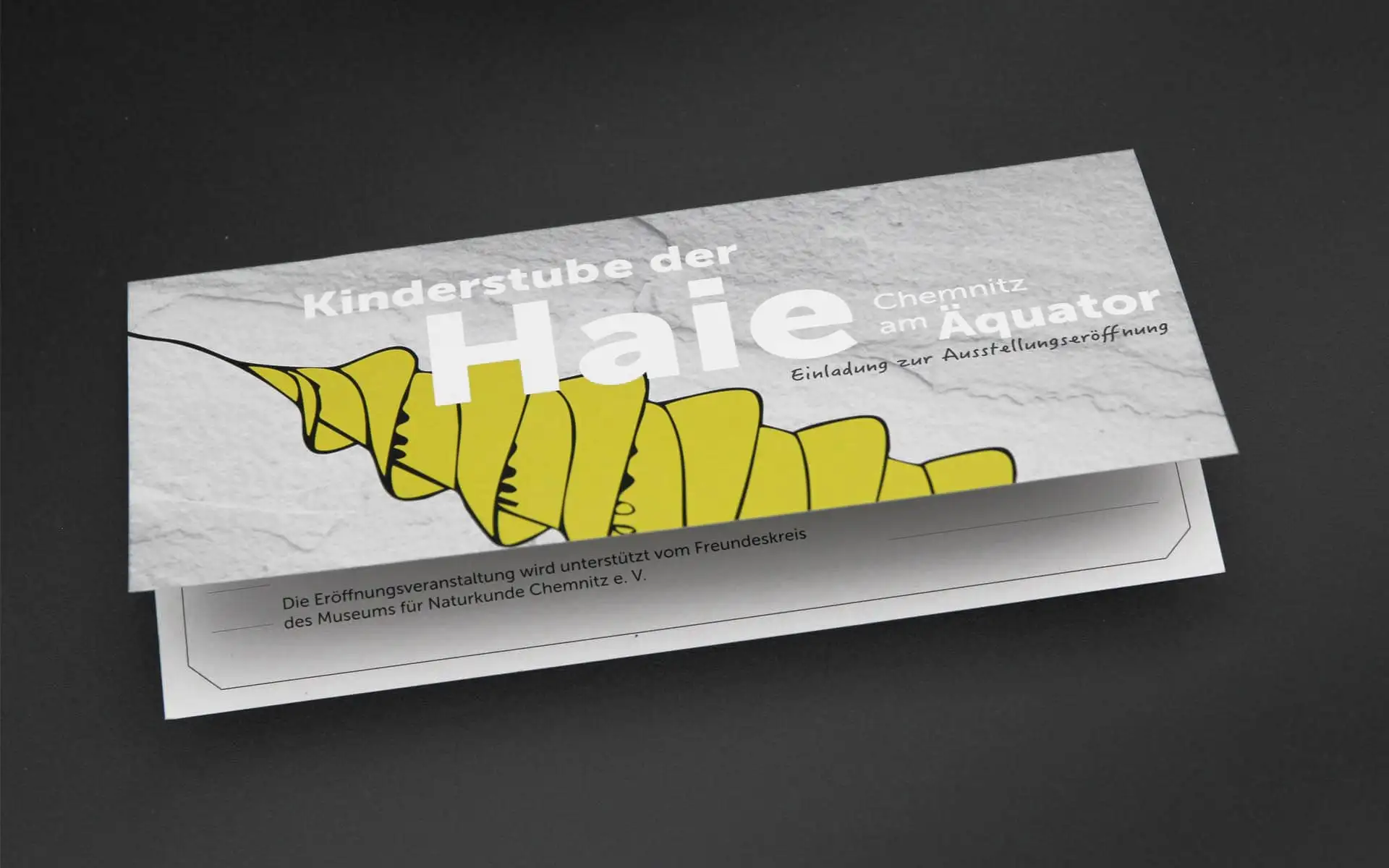 Einladungskarte „Kinderstube der Haie“ mit gelber Fossil-Illustration und großem Titel auf hellem Hintergrund.