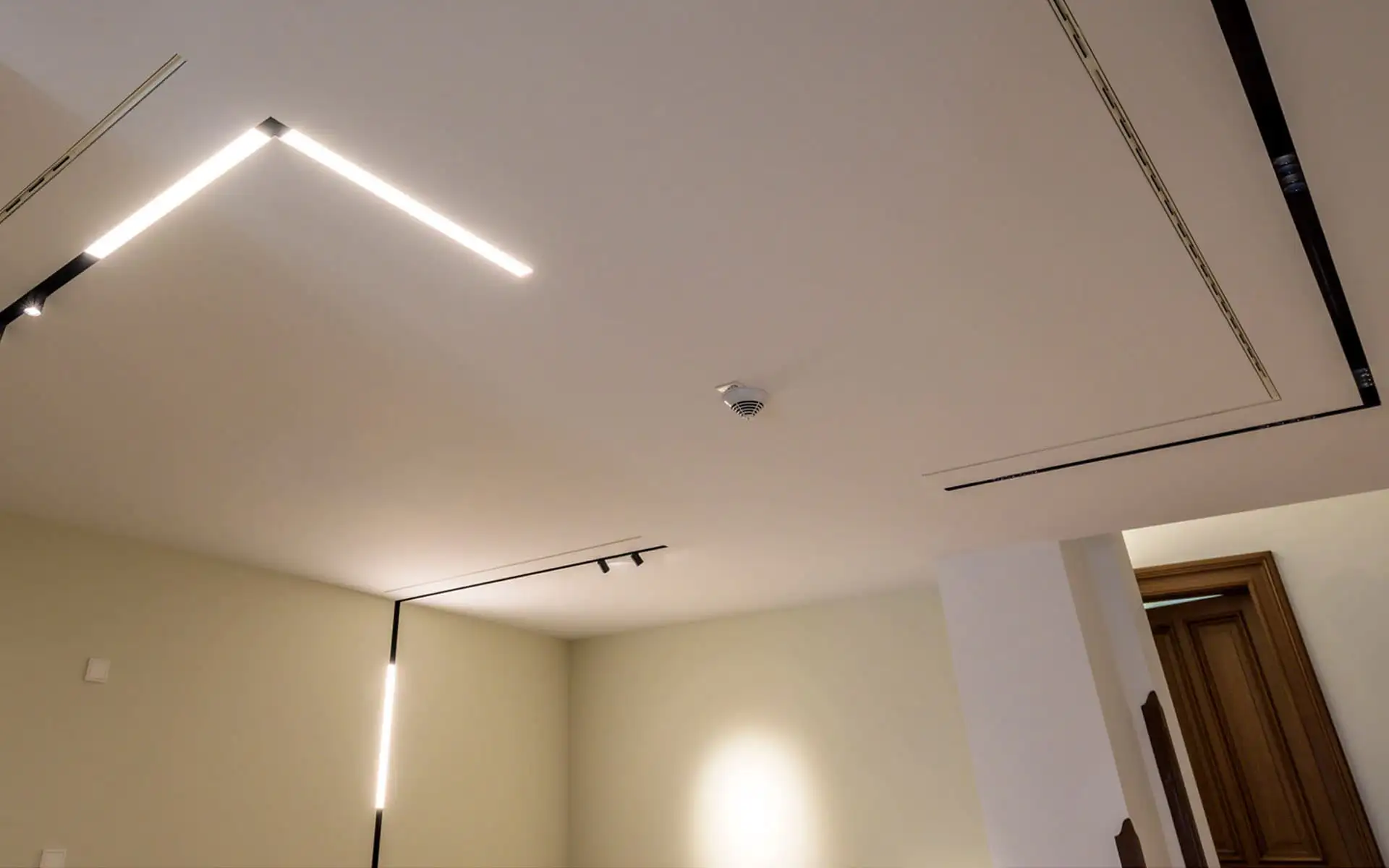 Decke mit linearem Lichtsystem und schlichten, hellen Wandflächen