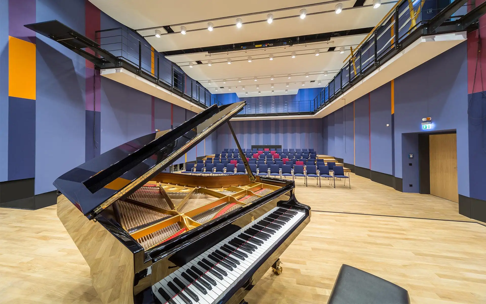 Konzertsaal der Musikschule Chemnitz: Flügel im Vordergrund, umlaufende Galerie und farbige Akustikpaneele.