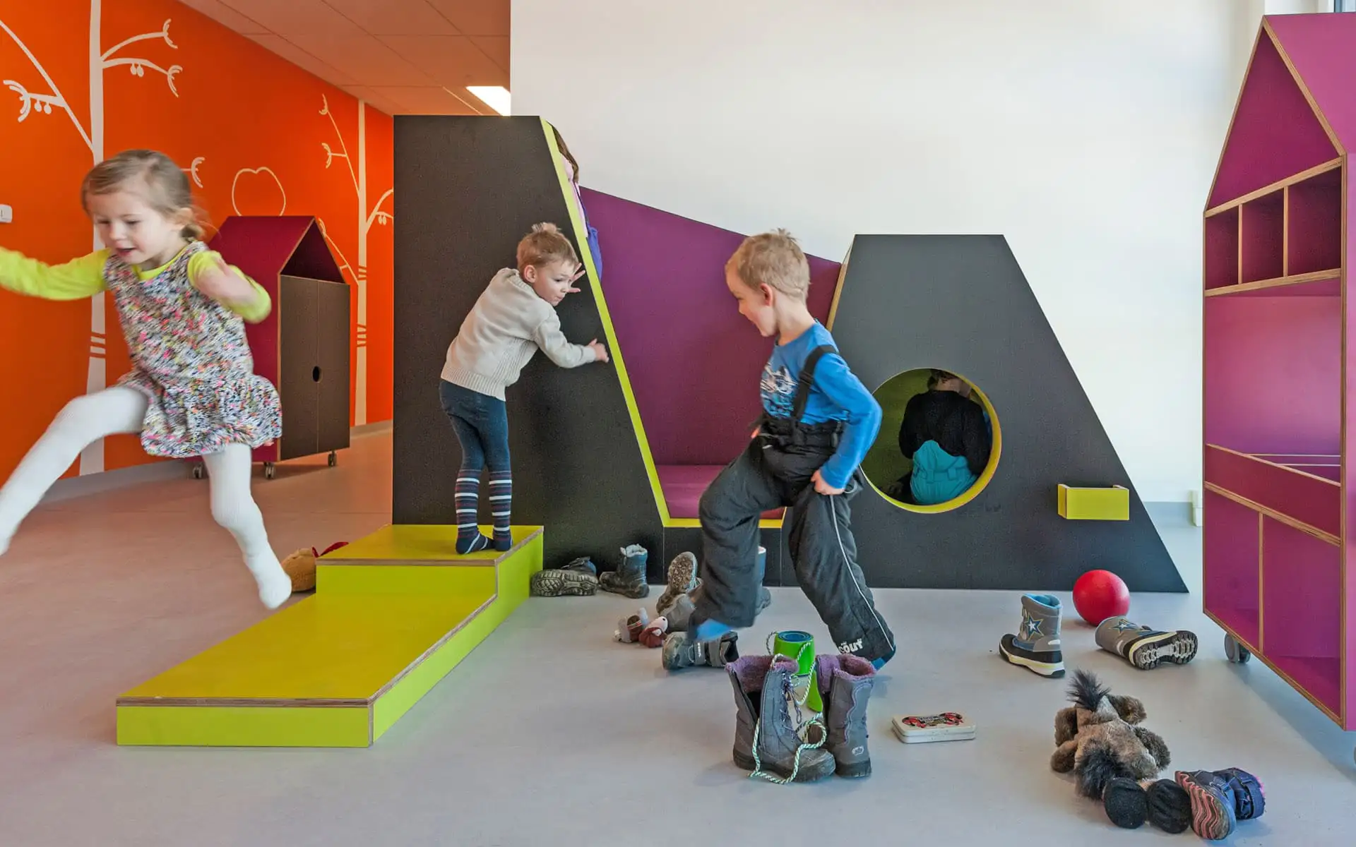 Kinder spielen an einer farbigen Spiellandschaft in einem Gruppenraum