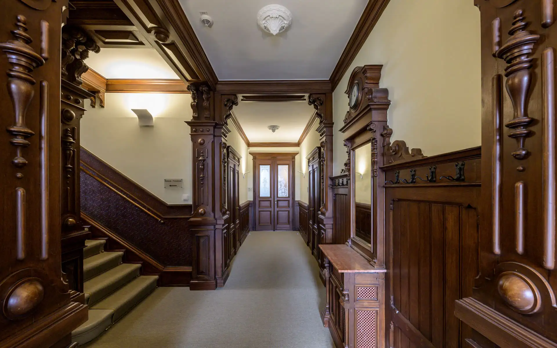Historischer Flur mit dunkler Holzvertäfelung, Treppe und Türen