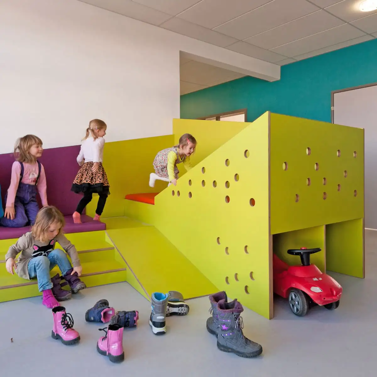 Kinder spielen auf einer erhöhten Plattform mit Rampe und Stauraum