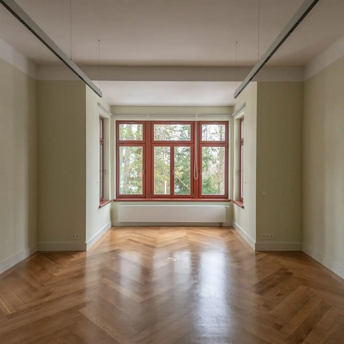 Leerer Raum mit Fischgrätparkett und großem Fenster