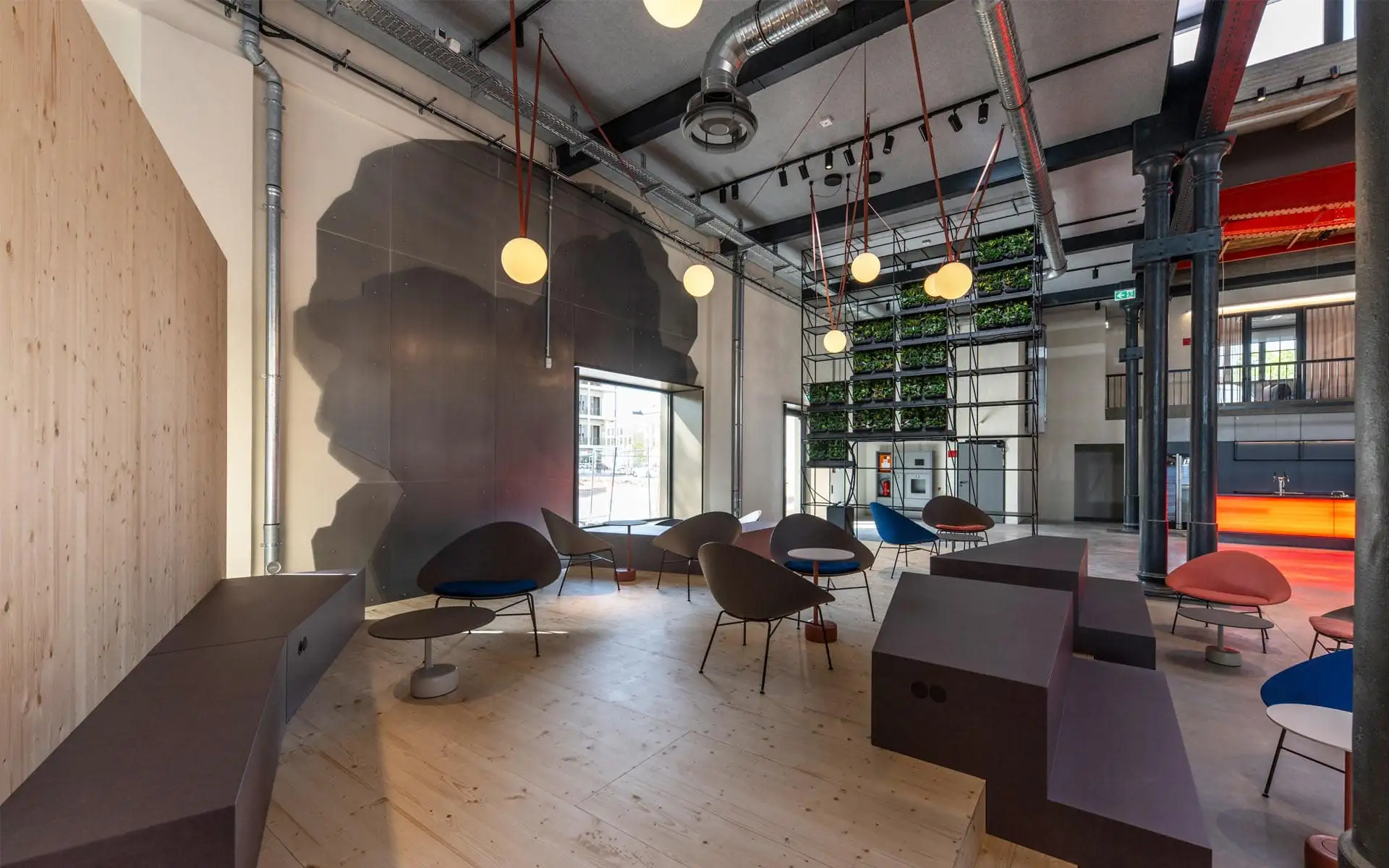 Loungebereich mit runden Leuchten, Pflanzenwand und Sitzgruppen