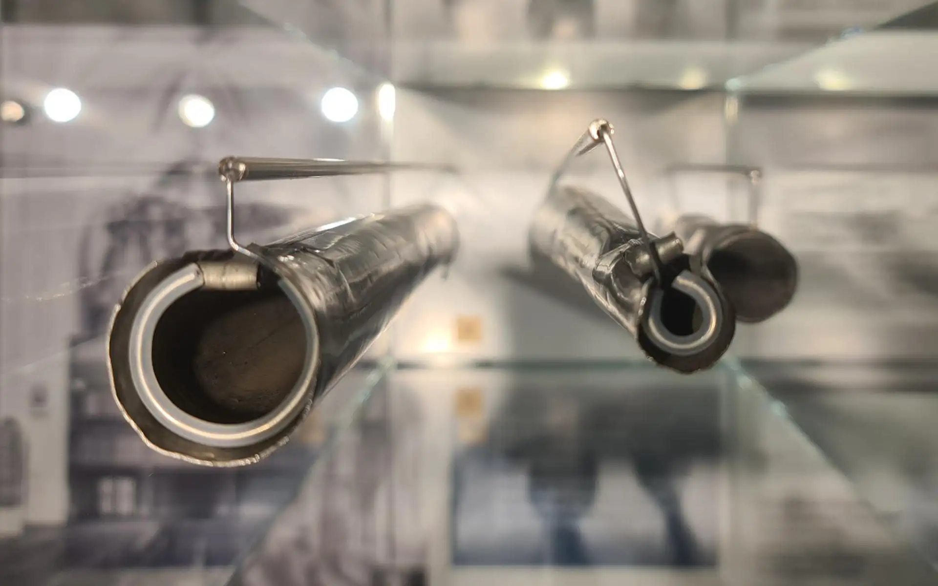 Zylindrische technische Exponate aus Metall, in einer Glasvitrine schwebend montiert.