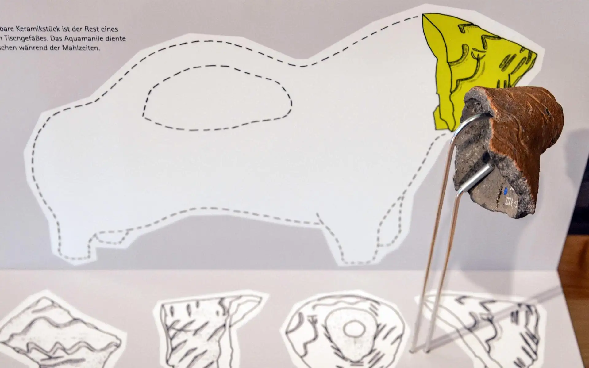 Keramikfragment mit schematischer Zeichnung der ursprünglichen Gefäßform im Hintergrund.