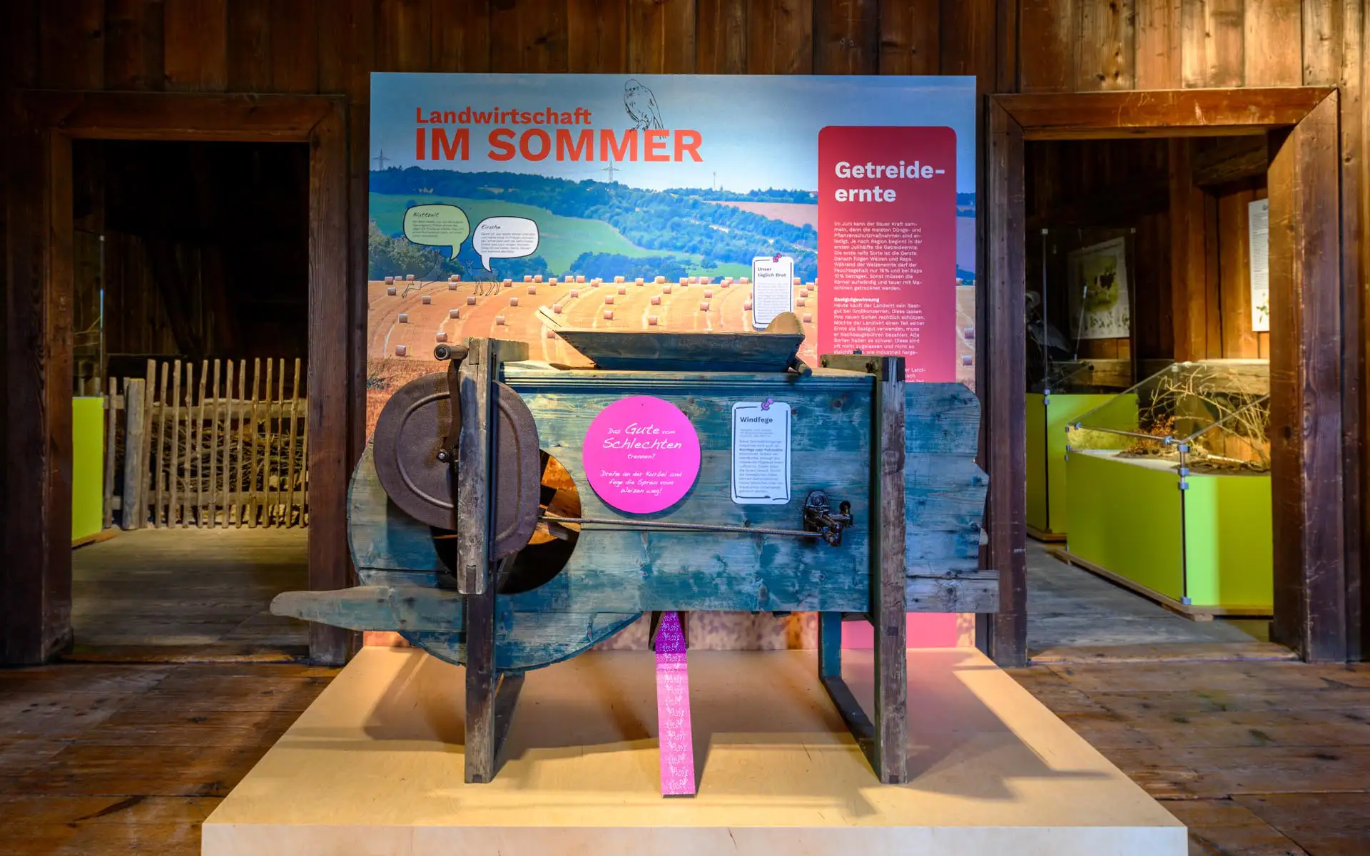 Historisches landwirtschaftliches Gerät vor Ausstellungstafel zum Thema Landwirtschaft im Sommer.